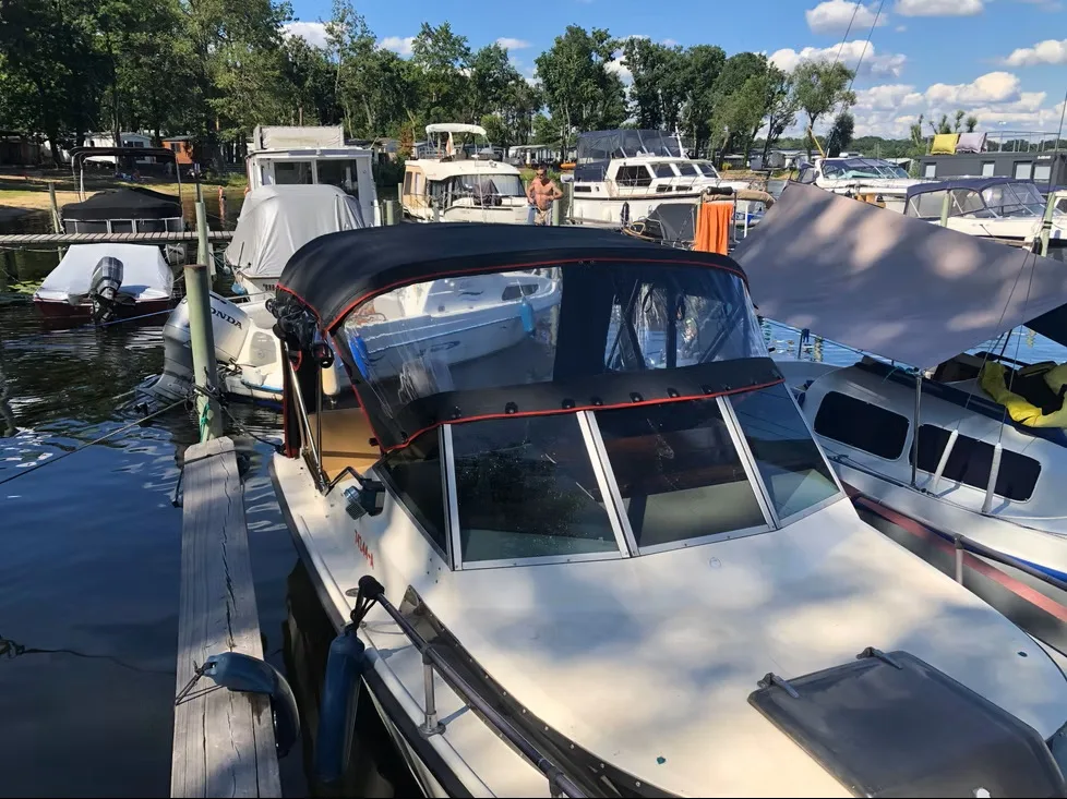 Motorboot im Hafen mit dunkelblauem Fahrverdeck und transparenten Fenstern.