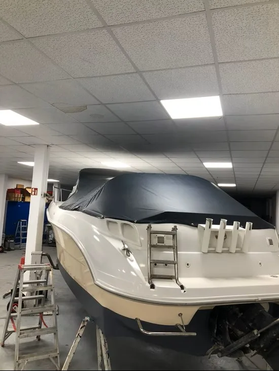 Weißes Motorboot in einer Werkstatt mit dunkler Abdeckung über dem Cockpit.