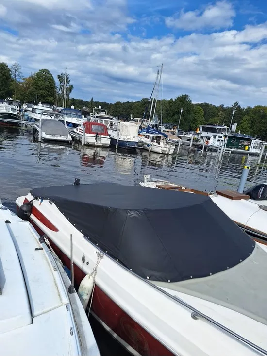 Rot-weißes Motorboot im Hafen mit flacher schwarzer Cockpitpersenning.