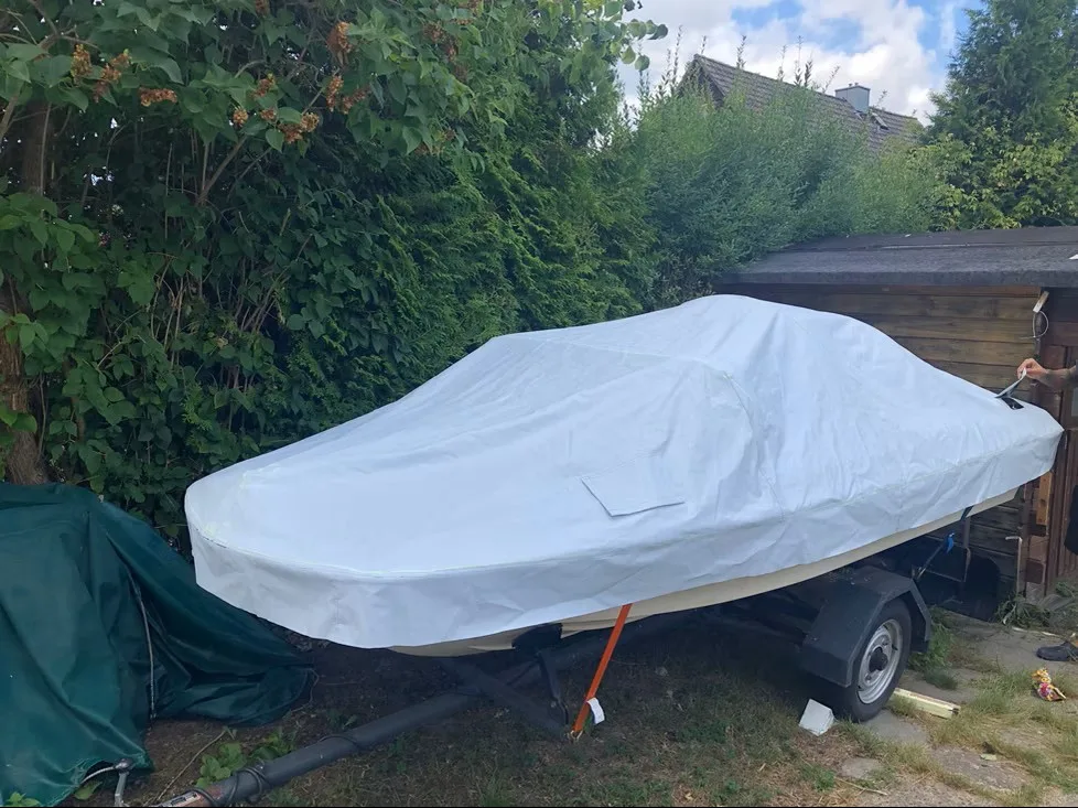 Boot auf einem Trailer mit weiß-grüner vollständig geschlossener Abdeckung.