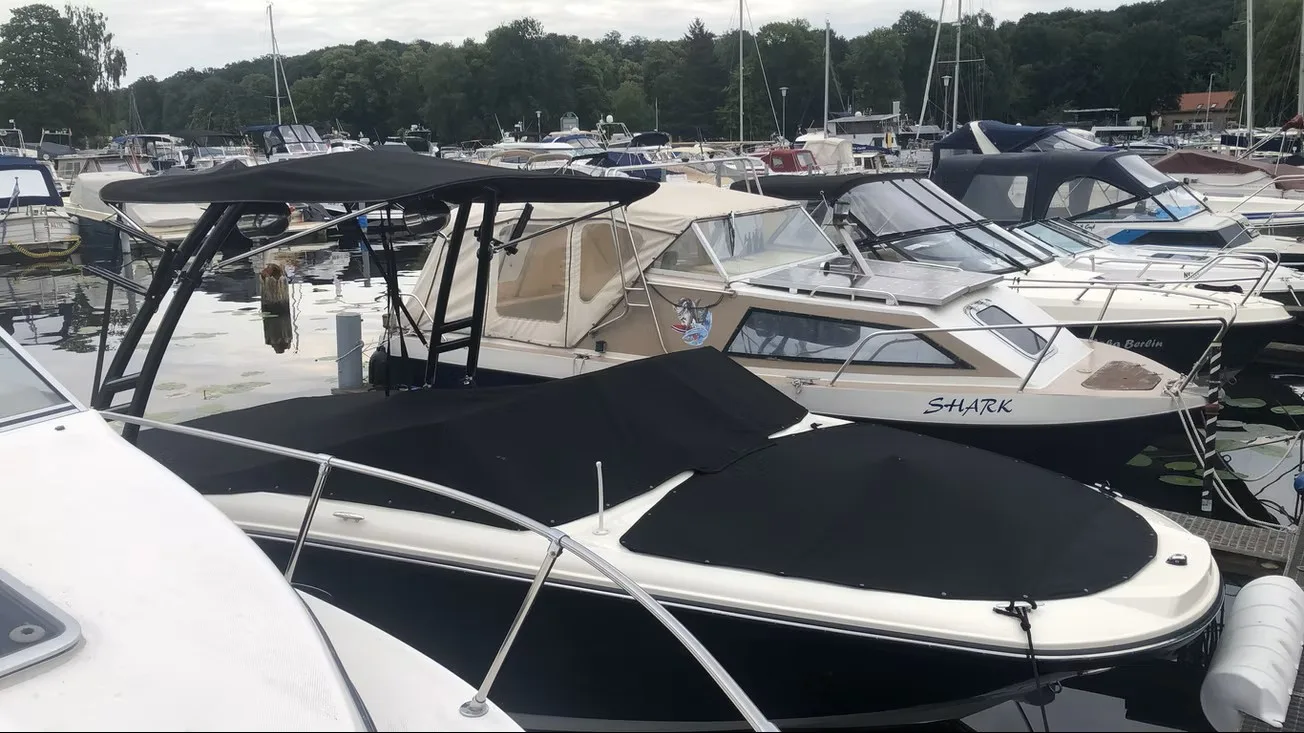 Weißes Motorboot im Hafen mit flacher schwarzer Cockpitabdeckung.