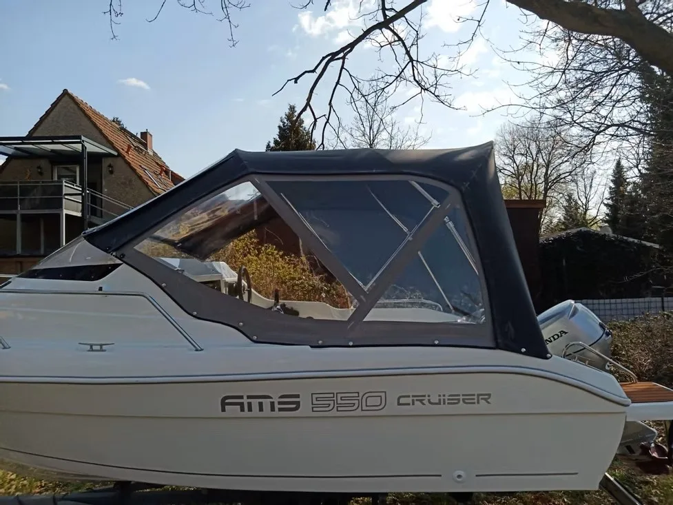 Beiges Kajütboot mit dunkelblauem Fahrverdeck und großem Seitenfenster.