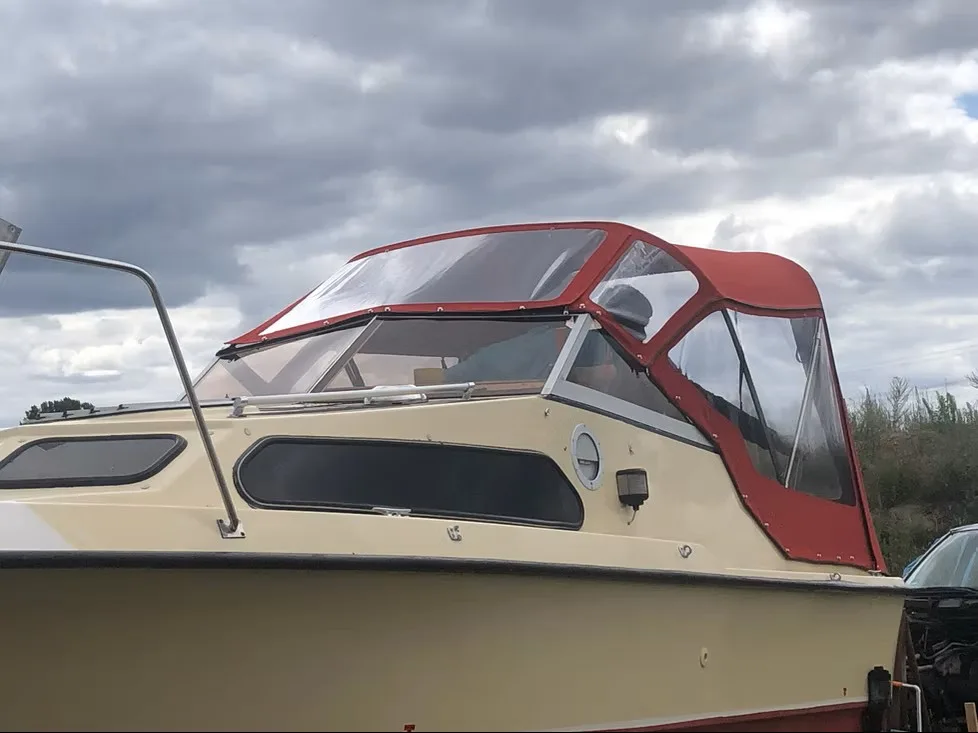 Beiges Motorboot mit bordeauxfarben eingefasstem transparentem Fahrverdeck.