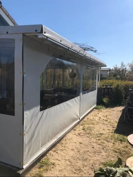 Lange weiße Terrasseneinhausung mit mehreren transparenten PVC-Fenstern.