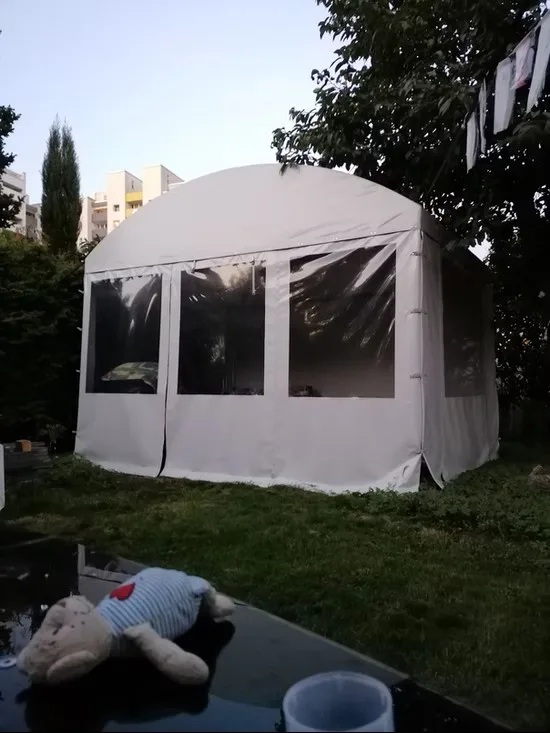 Freistehender Gartenpavillon mit weißer Einhausung und großen klaren PVC-Fenstern.
