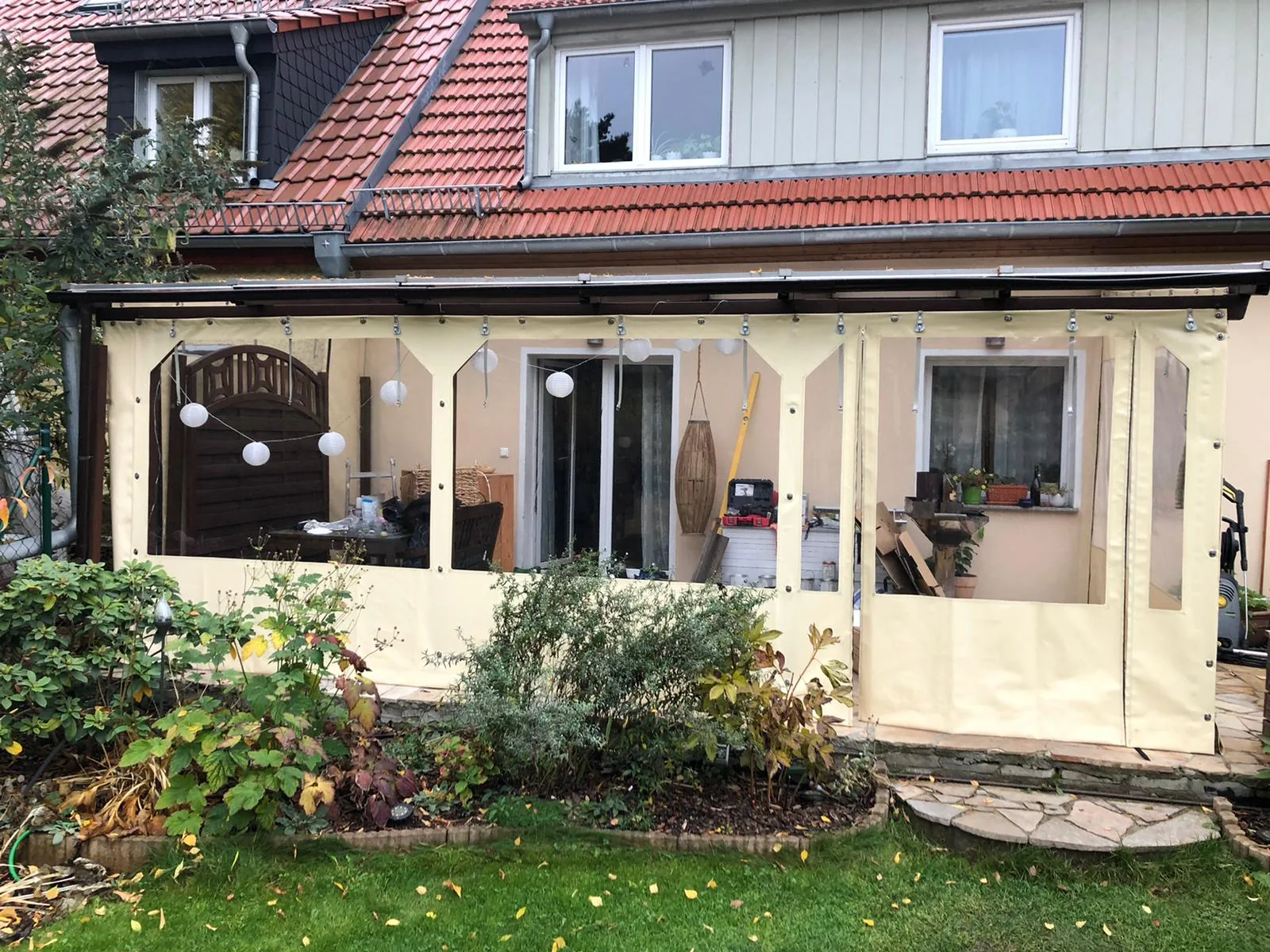 Helle Terrasseneinhausung mit klaren PVC-Flächen an einem Wohnhaus.
