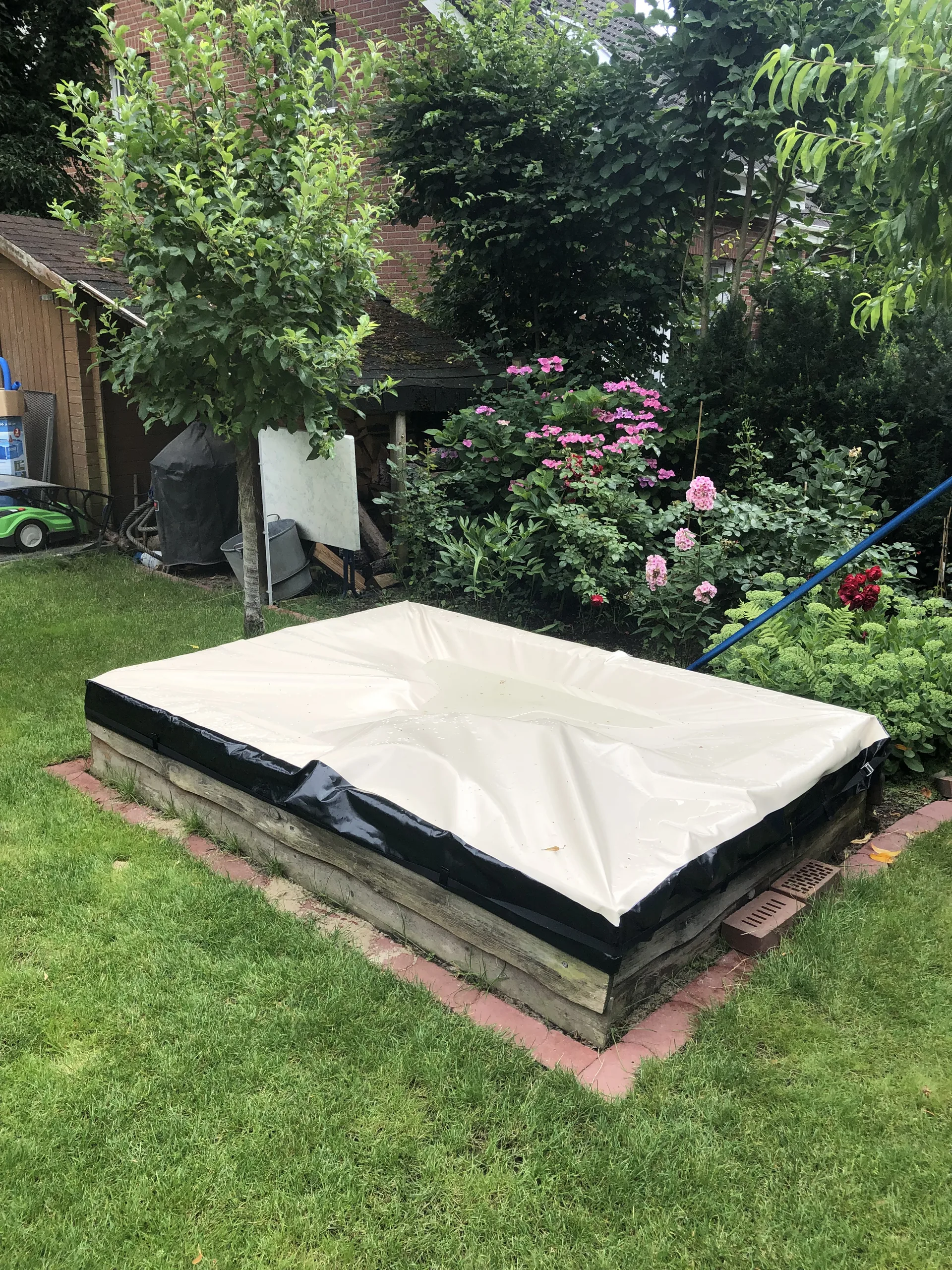 Beige Abdeckung mit dunklem Rand auf einer rechteckigen Außenfläche.