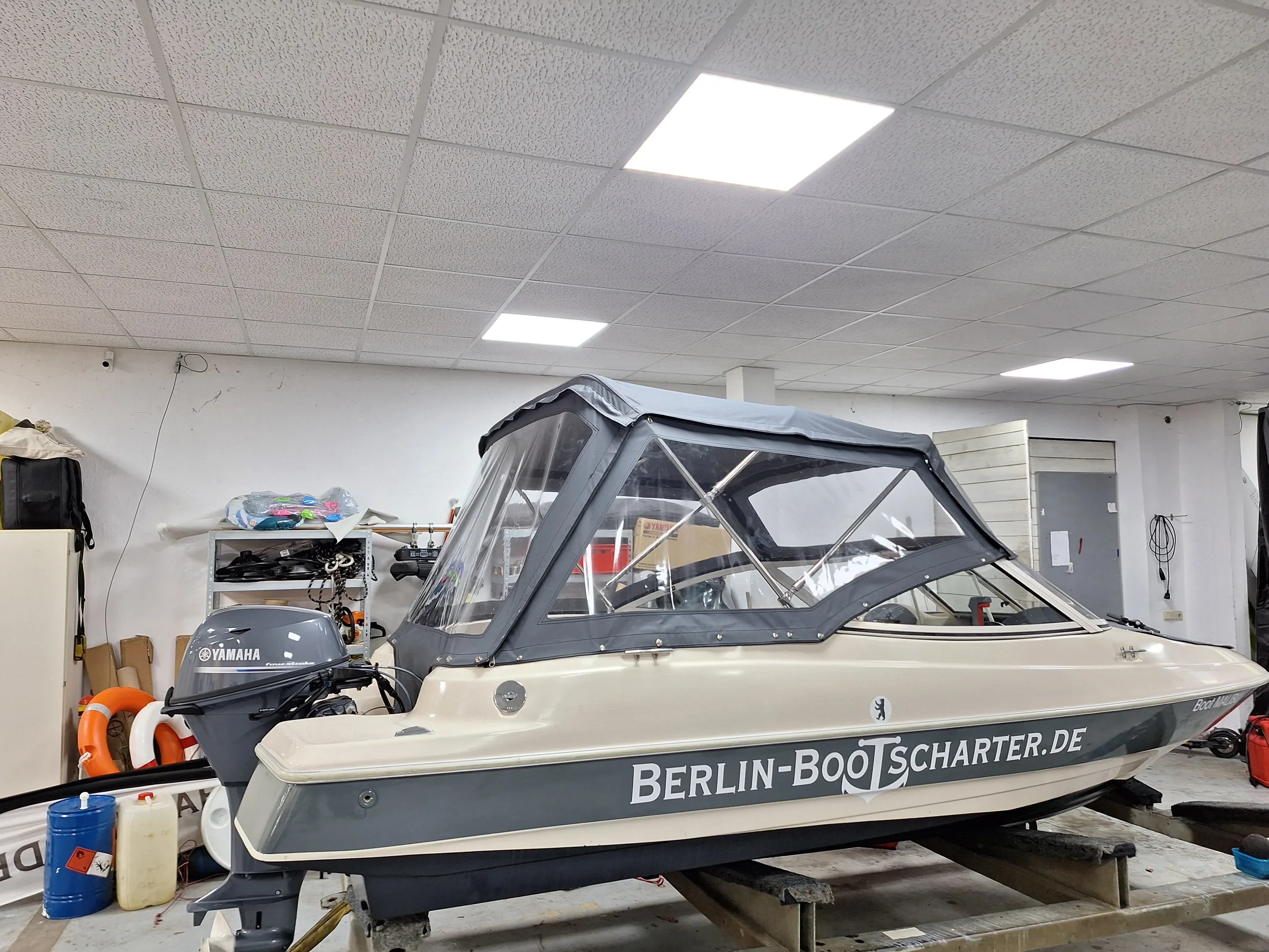 Motorboot mit montierter anthrazitfarbener Fahrpersenning und klaren Fensterflächen in der Werkstatt.