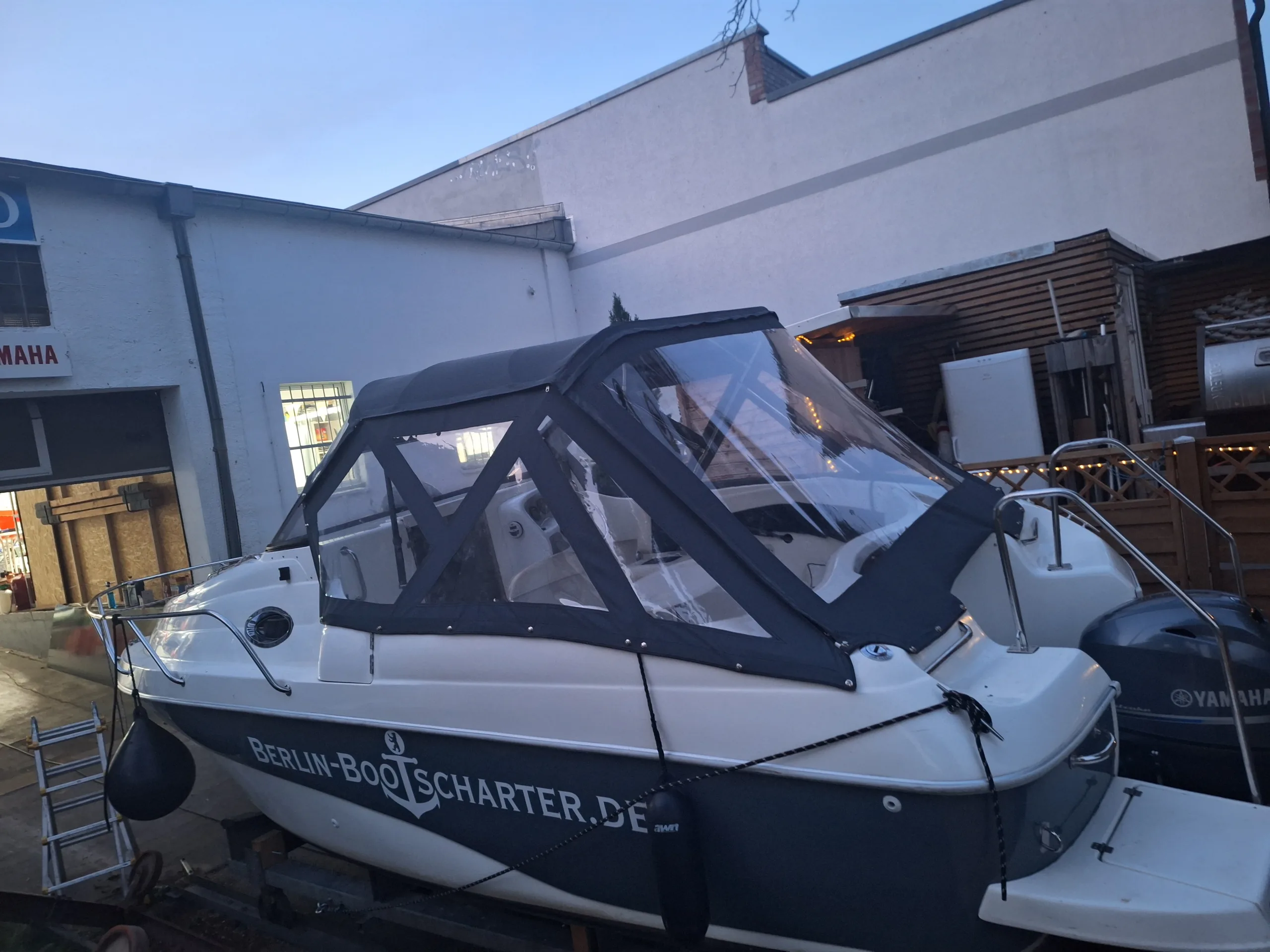 Motorboot mit vollständig geschlossener Fahrpersenning und mehreren klaren Sichtfenstern.