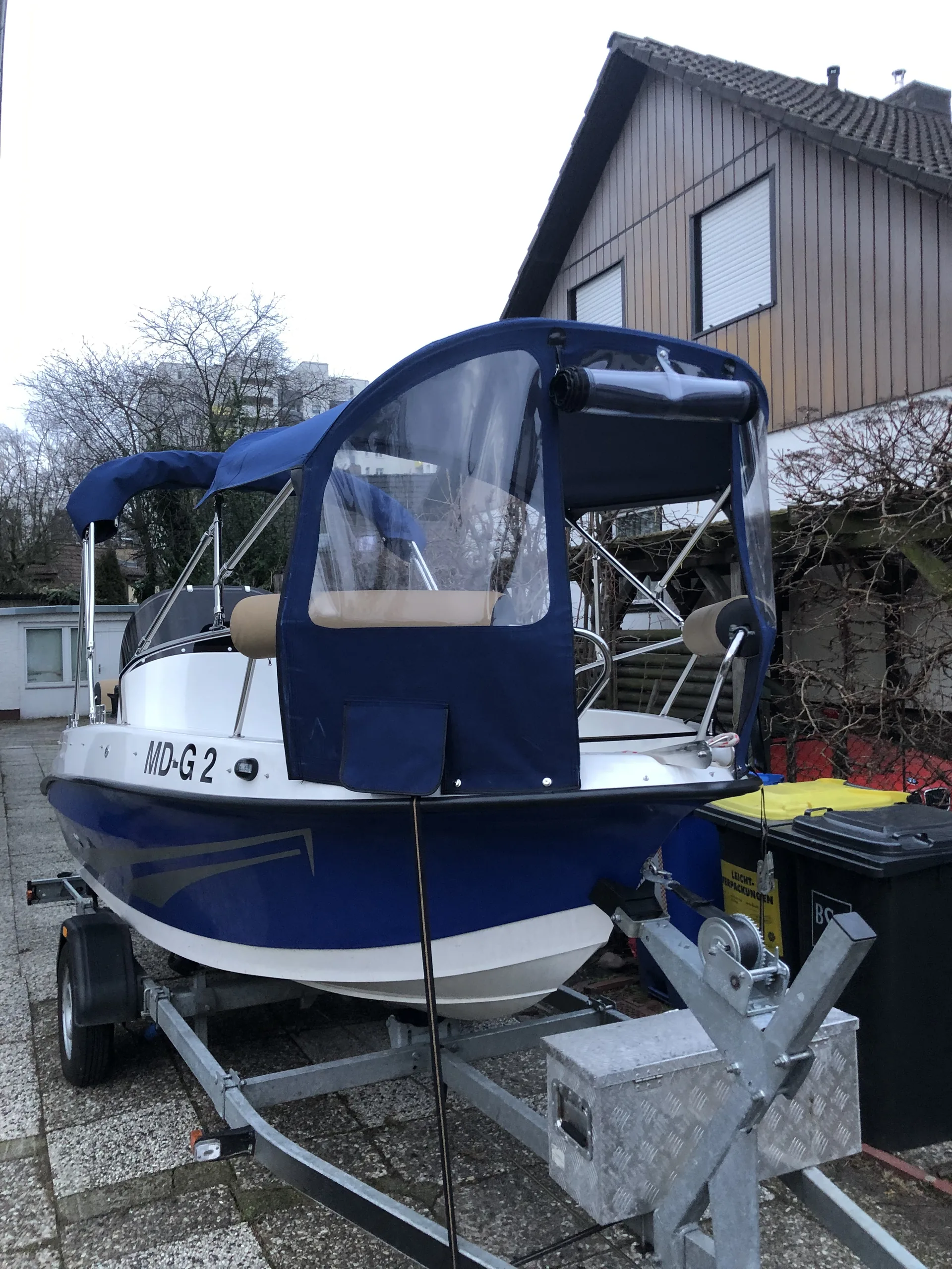 Heckansicht eines blauen Motorboots mit dunkelblauer Fahrpersenning.