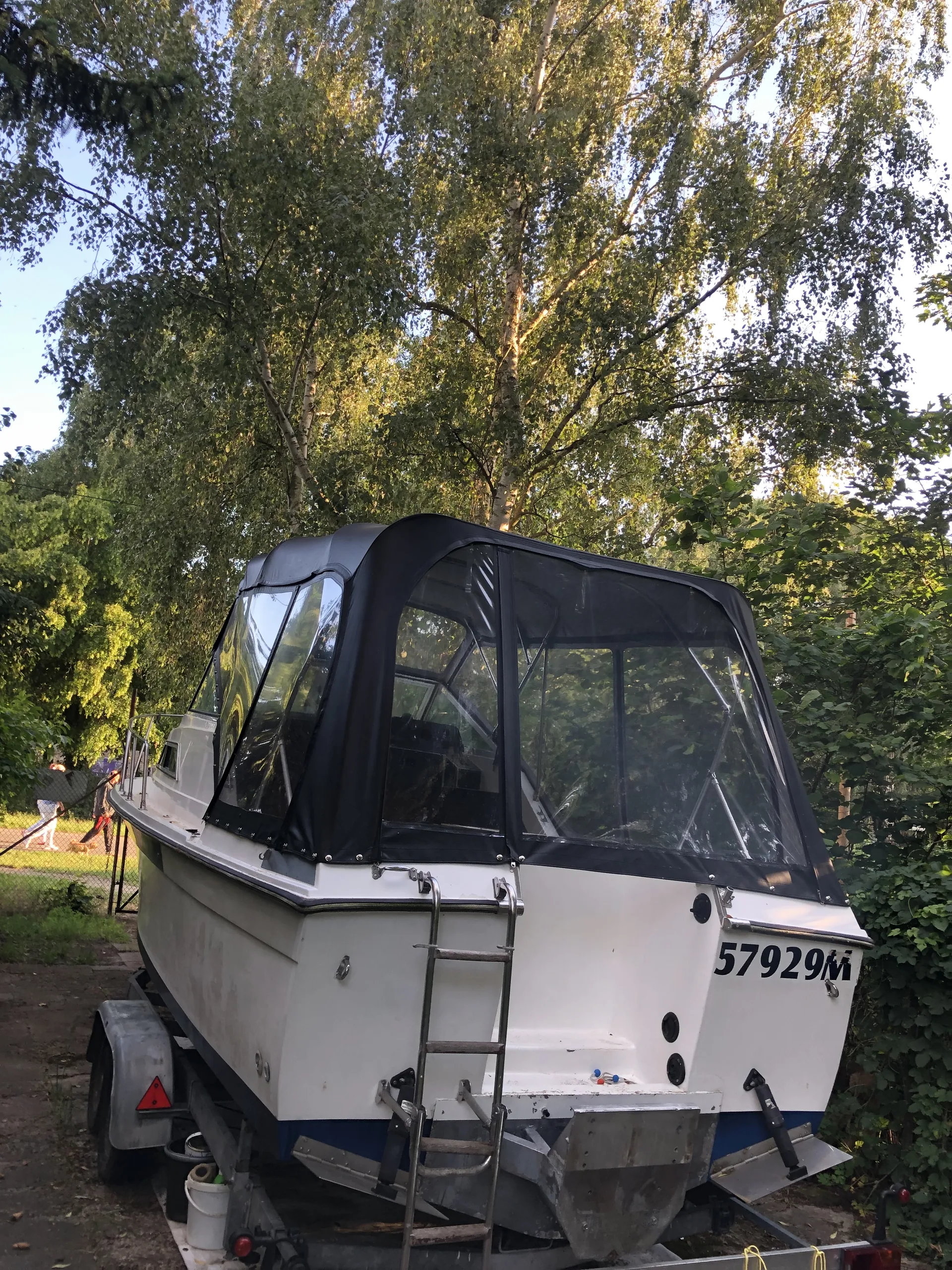 Helle Motoryacht mit dunkler Fahrpersenning und hohem transparentem Heckteil.