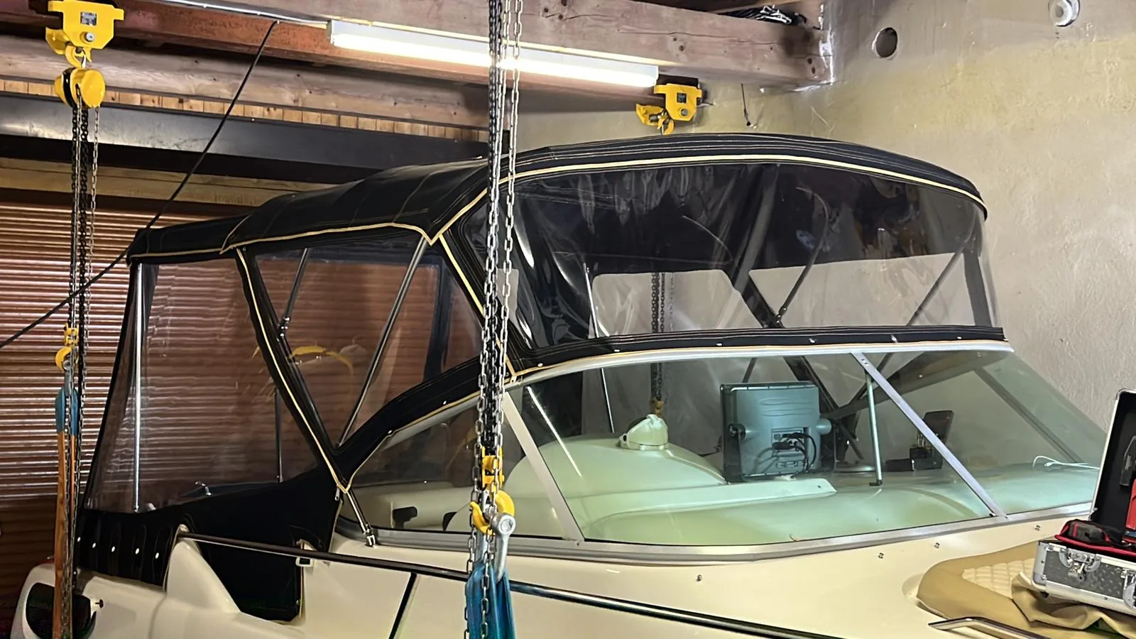 Dunkle Fahrpersenning mit transparenter Frontfläche auf einem Motorboot in der Werkstatt.
