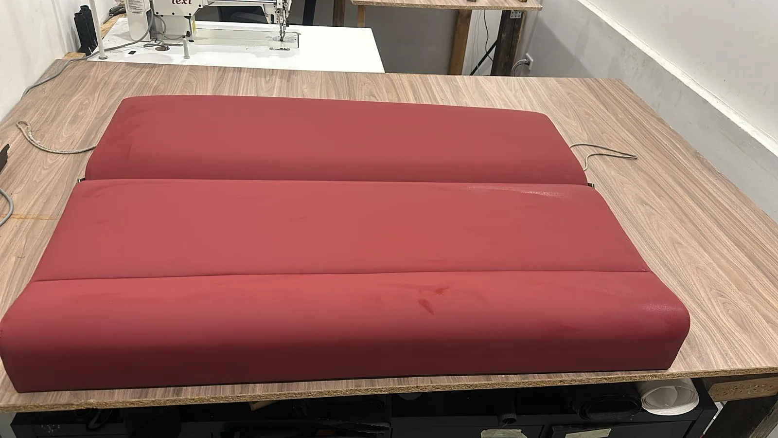Rote mehrteilige Liegepolster auf einem Boot mit Holzdeck.