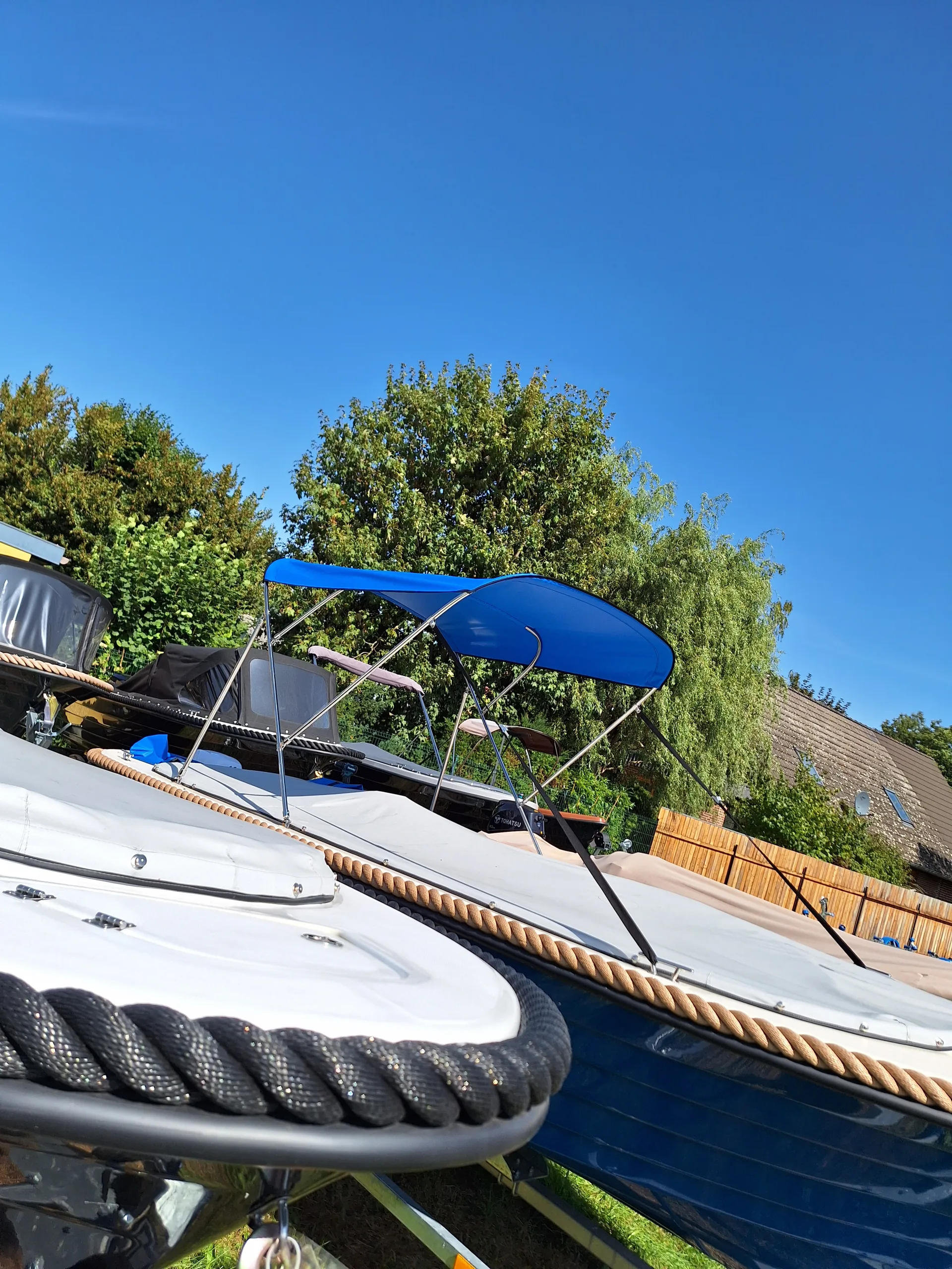 Weißes Motorboot mit blauem Bimini-Top über der Sitzgruppe.