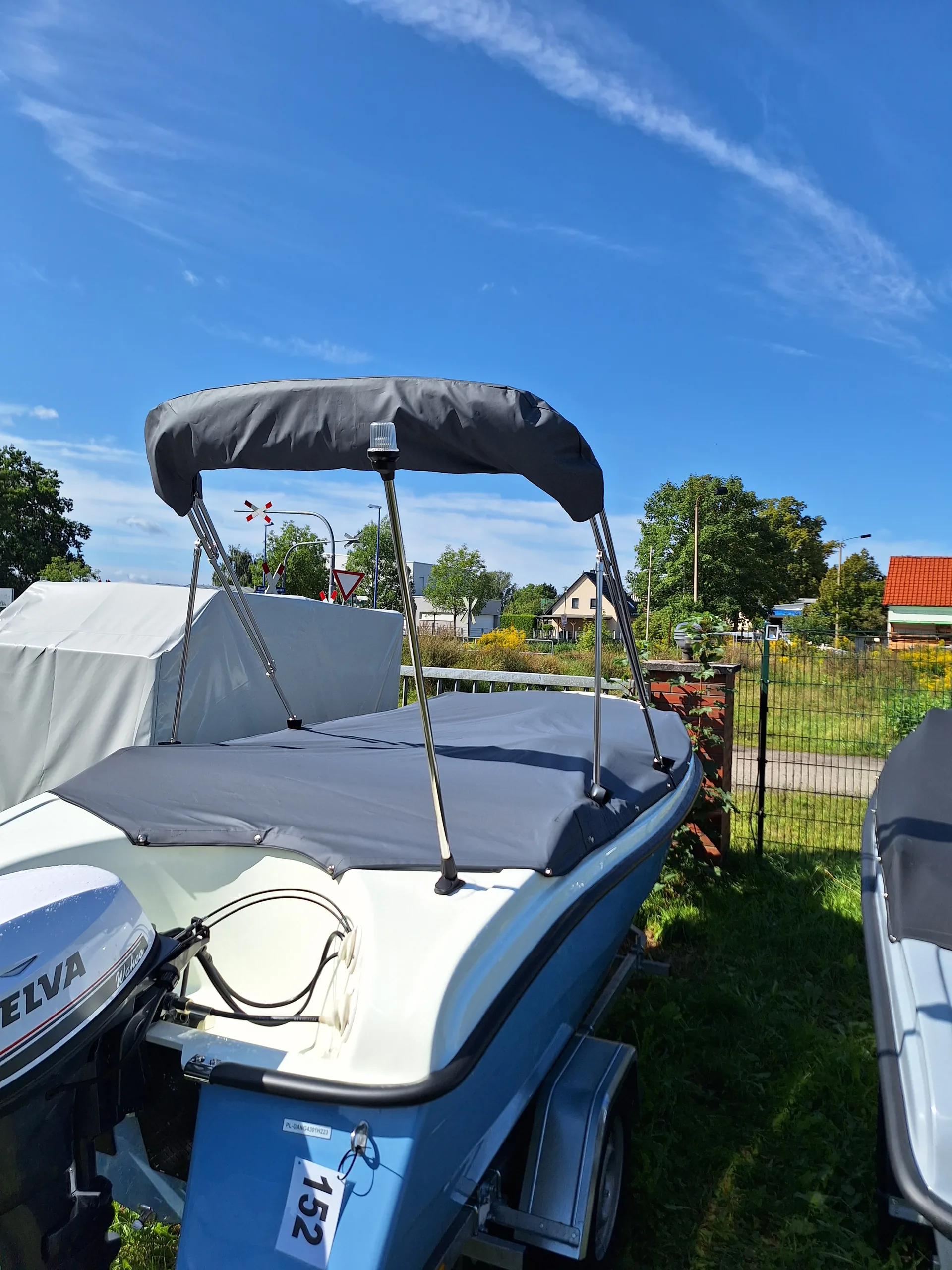 Kleines Motorboot mit dunklem Bimini-Top und aufgespanntem Gestänge.