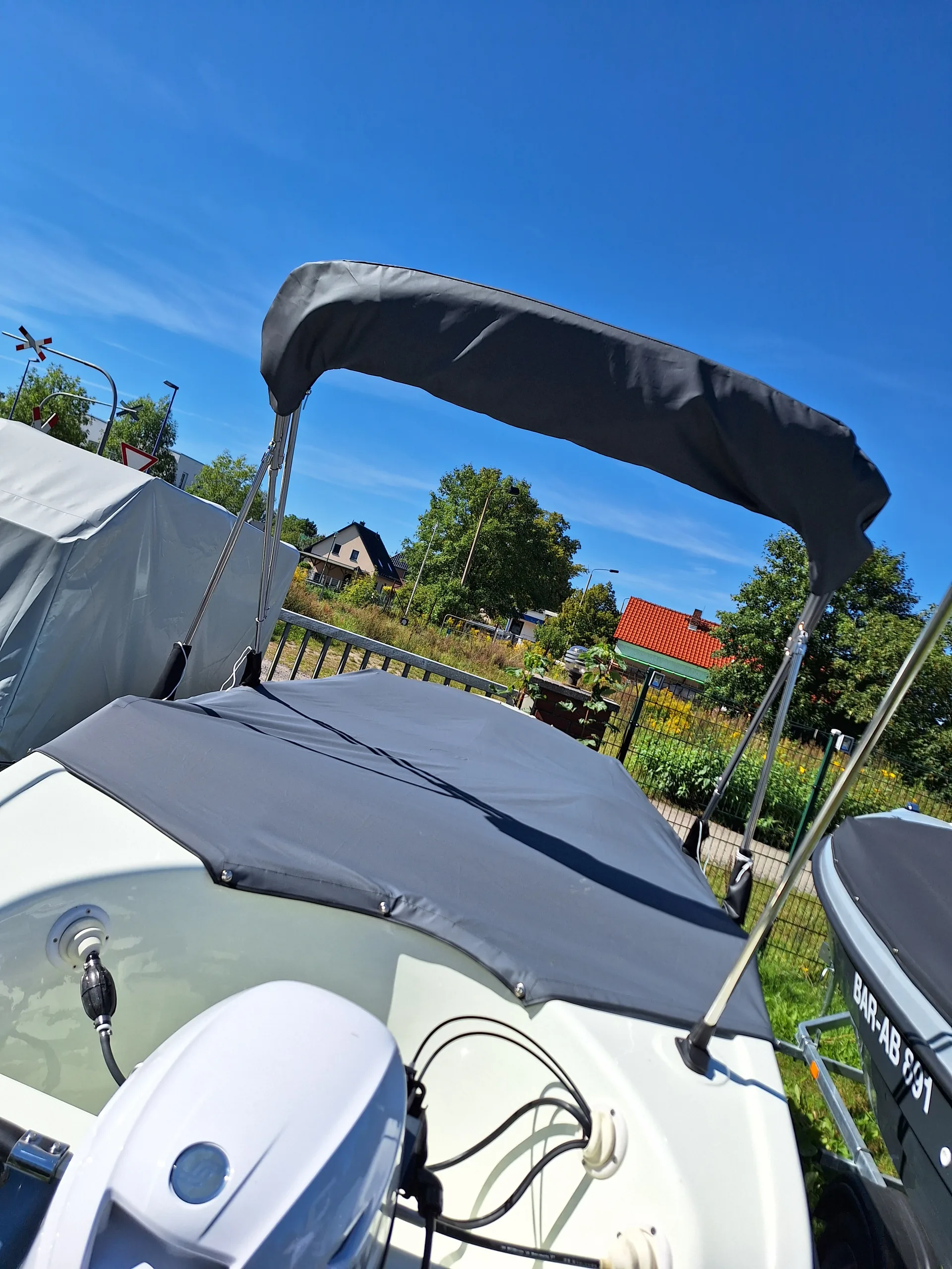 Dunkles Bimini-Top auf einem weißen Motorboot, vom Heck aus fotografiert.