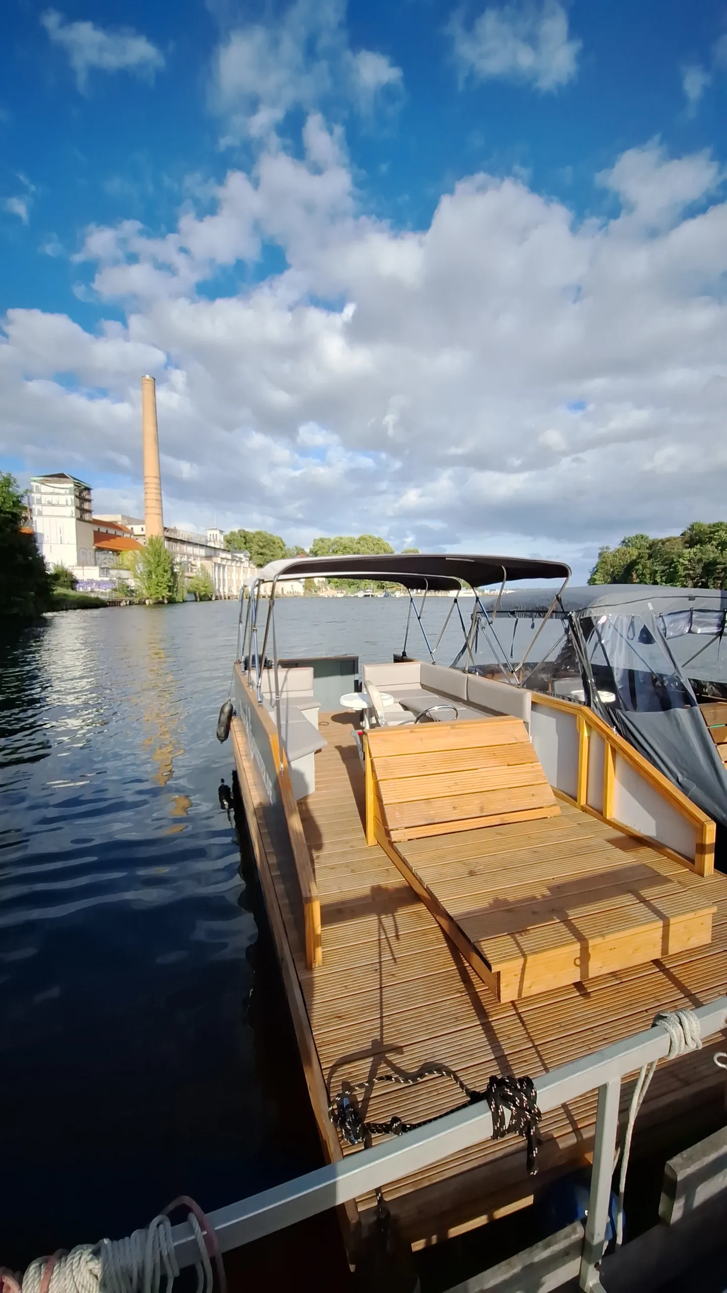 Offenes Motorboot mit dunklem Bimini-Top am Liegeplatz.