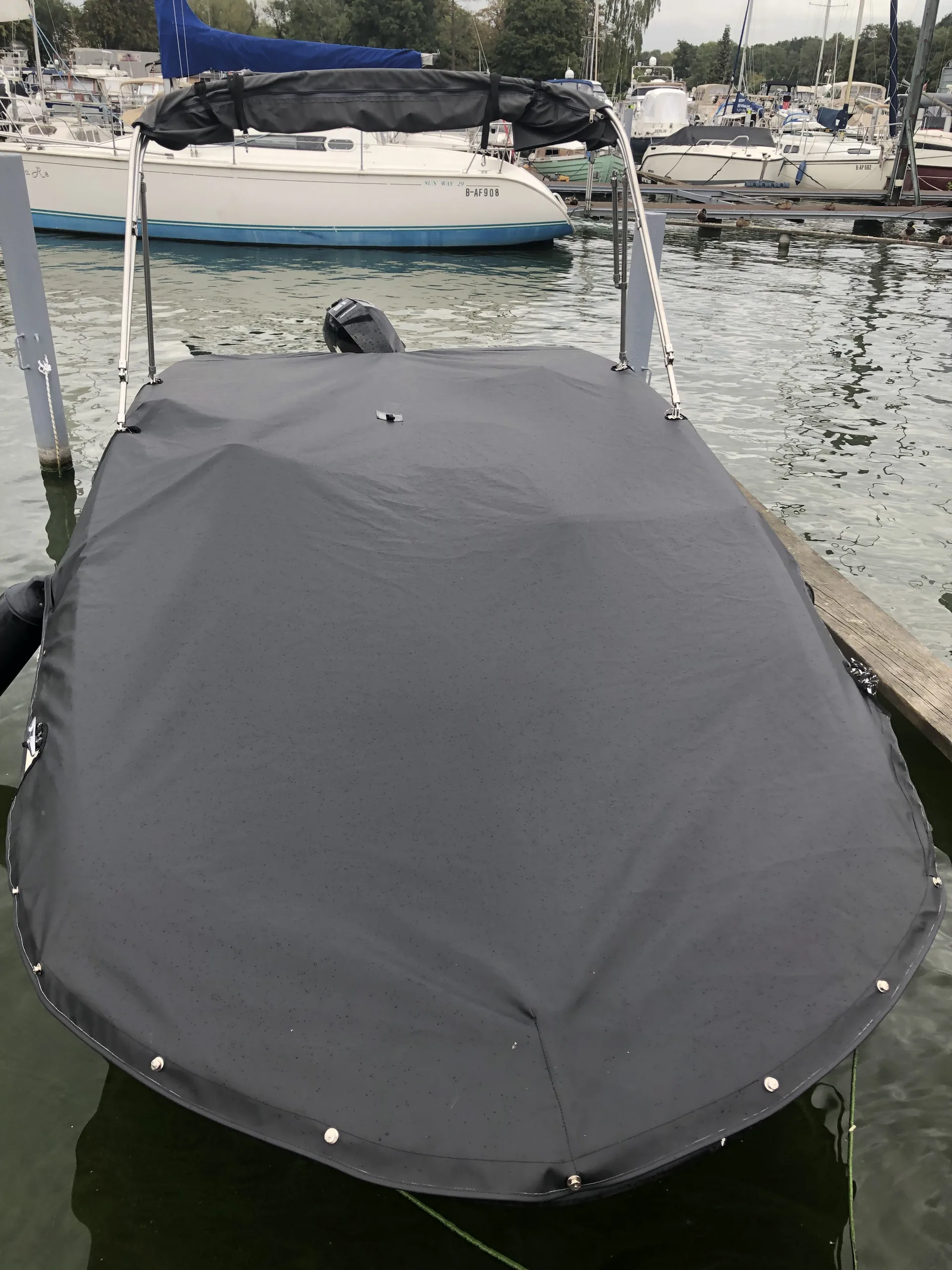 Boot am Steg mit großflächiger dunkelgrauer Abdeckplane.