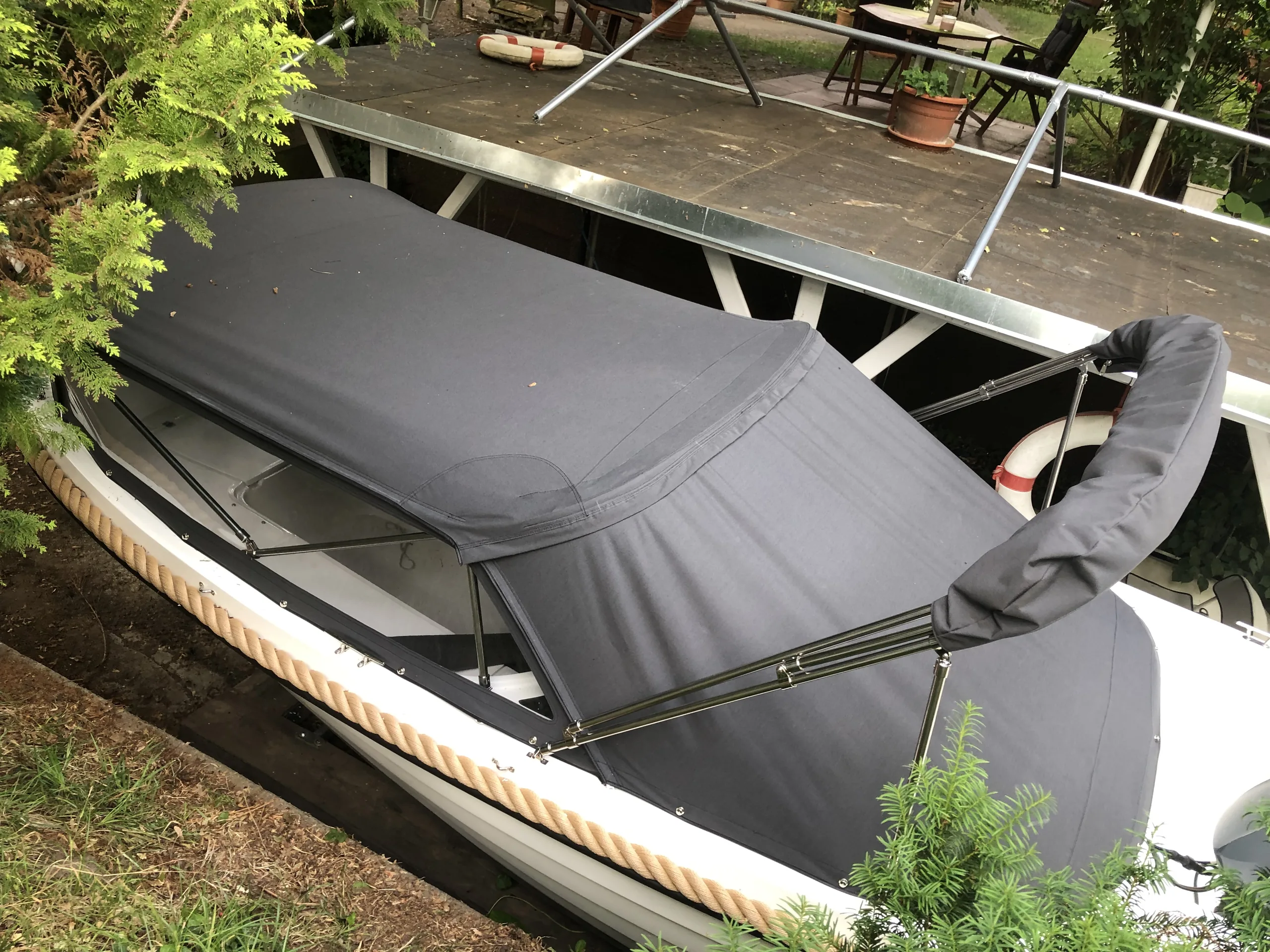 Längliches Boot mit flacher grauer Cockpitabdeckung unter einem Steg.