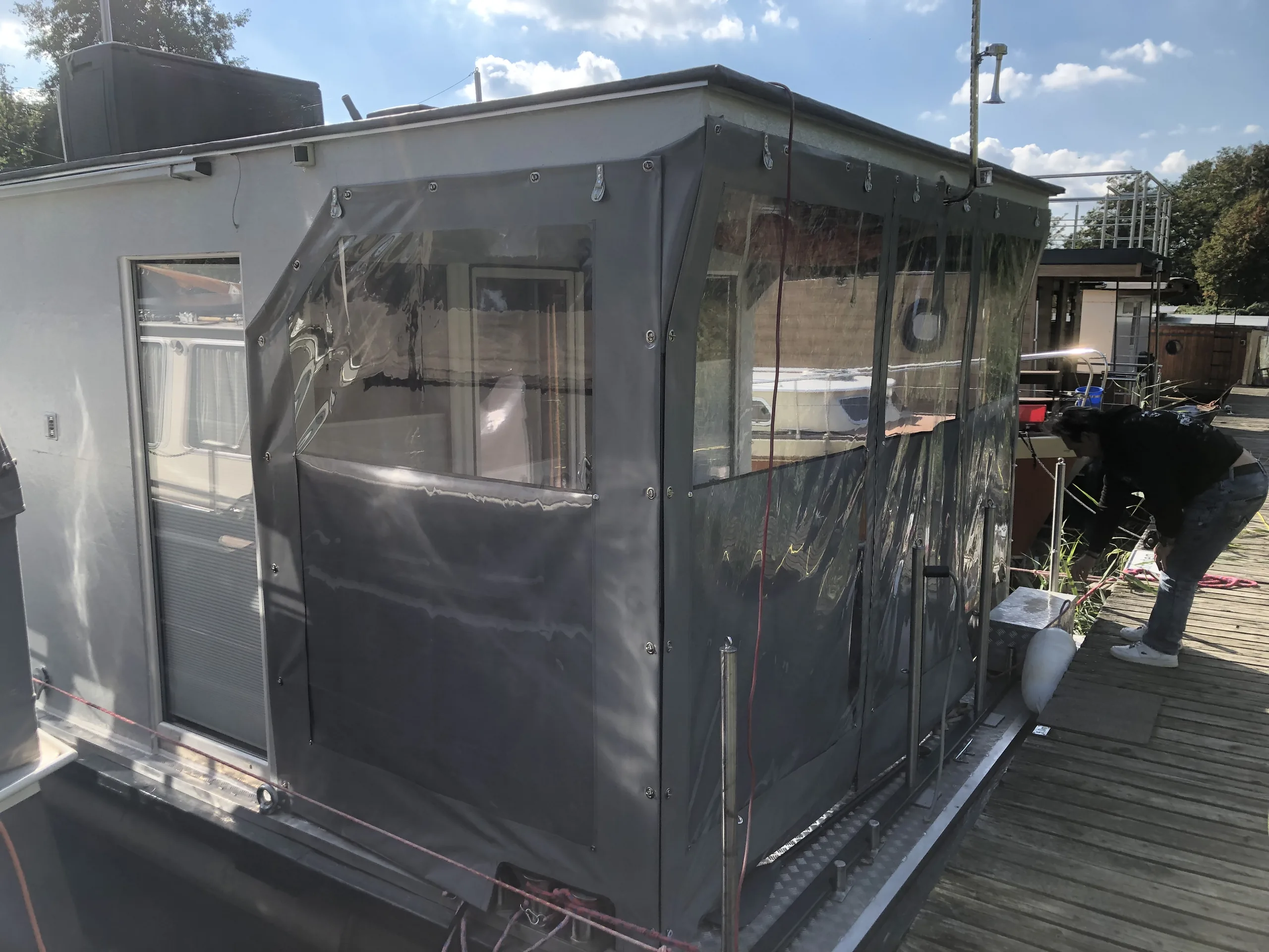 Graue PVC-Einhausung mit transparenten Flächen an einem Hausboot.