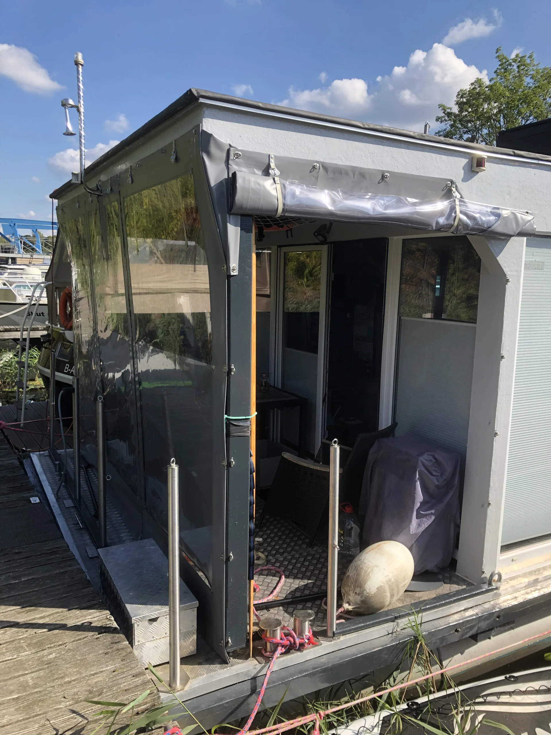 Transparentes Seitenteil einer grauen Hausboot-Einhausung.